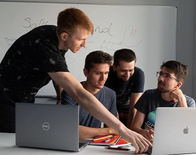 A group of developers looking at a laptop and talking.
