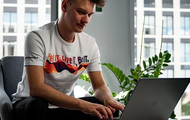 A boy in T-shirt "Feel it. Live it. Be it." working at the laptop.