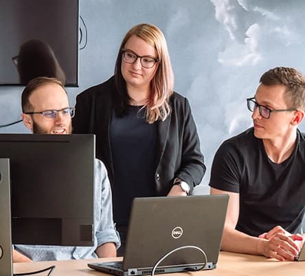 Programmer explains project to colleagues, works on laptop